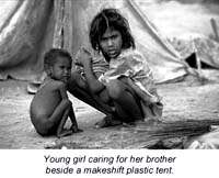 Young gorl caring for her brother next to plastic tent in Nicaragua